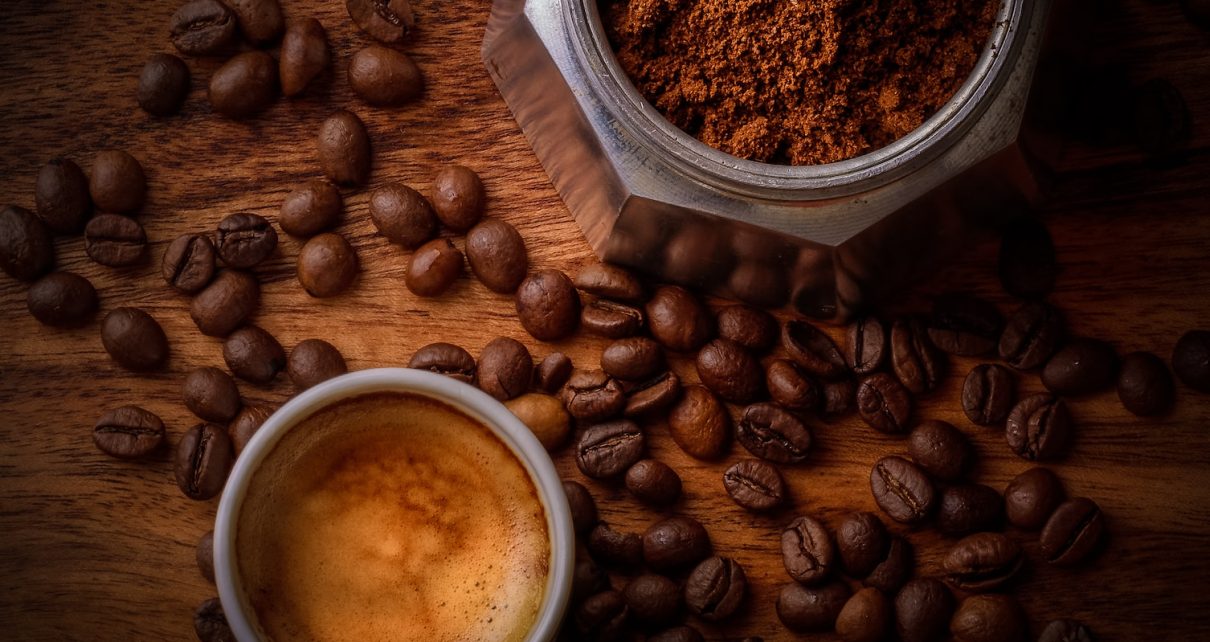 brown coffee beans beside white ceramic mug